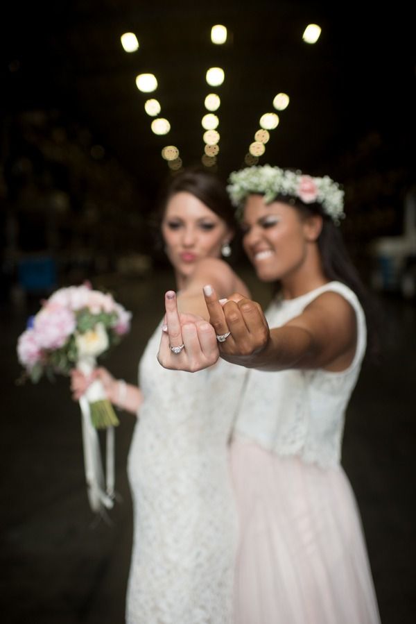 two brides pointing at the camera with flowers in their hair and wearing flower crowns