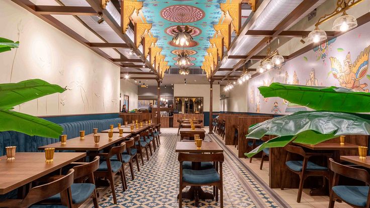 the interior of a restaurant with blue and gold decor on the walls, tables and chairs