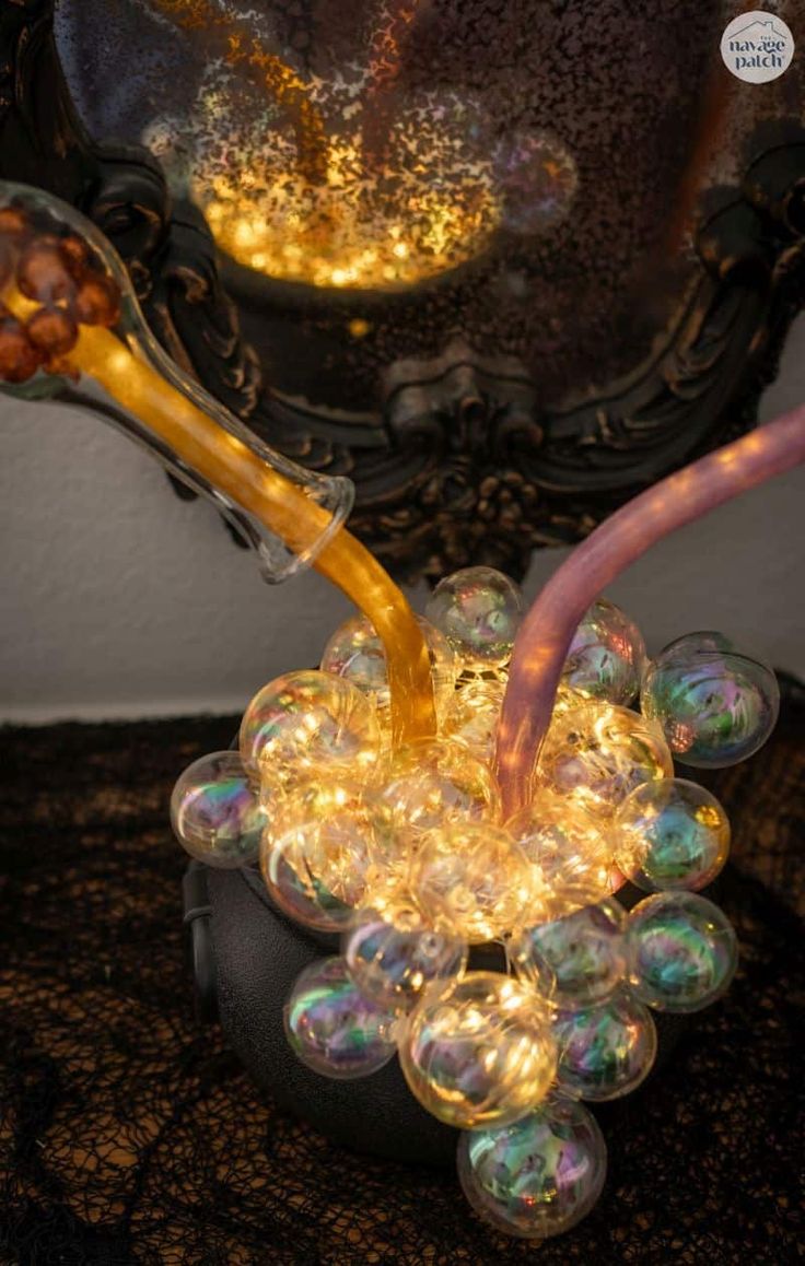 a glass jar filled with lots of light bulbs on top of a black table next to a mirror