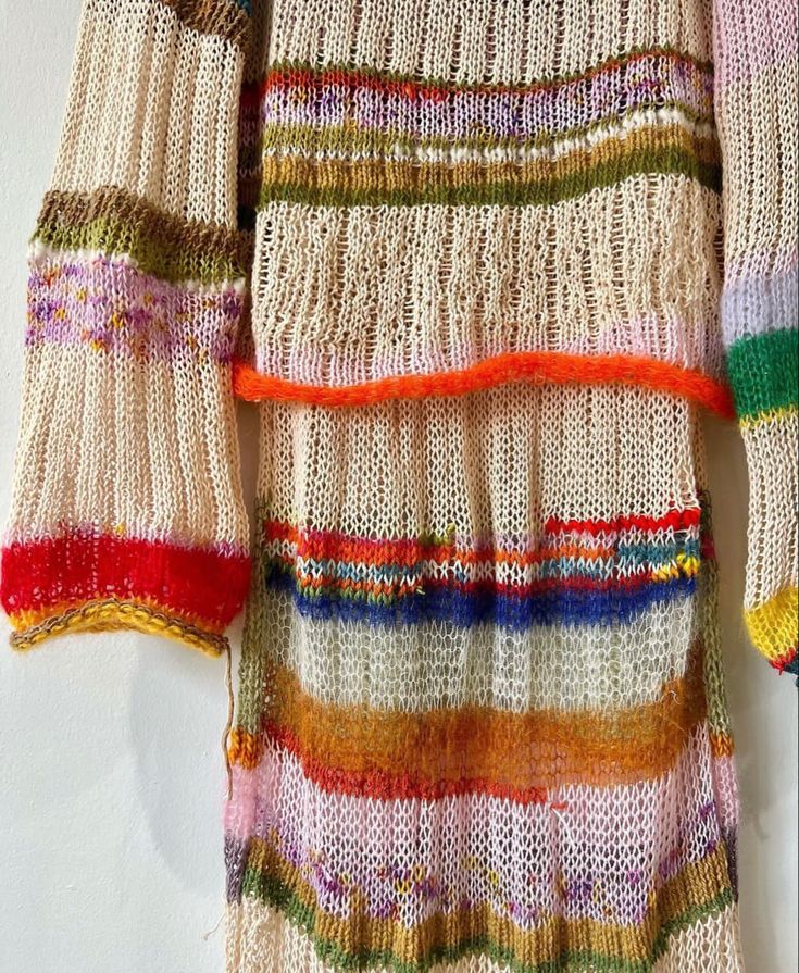 a multicolored sweater hanging on a white wall