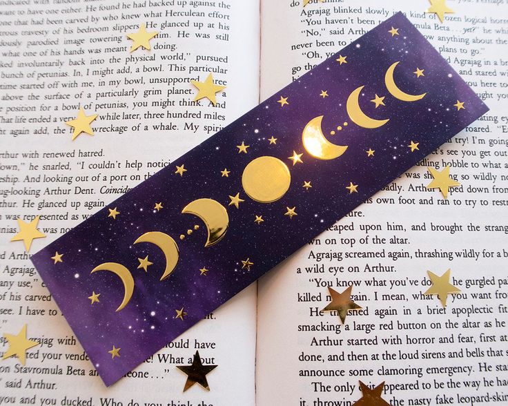 an open book with gold stars and crescents on it, next to a purple sticker