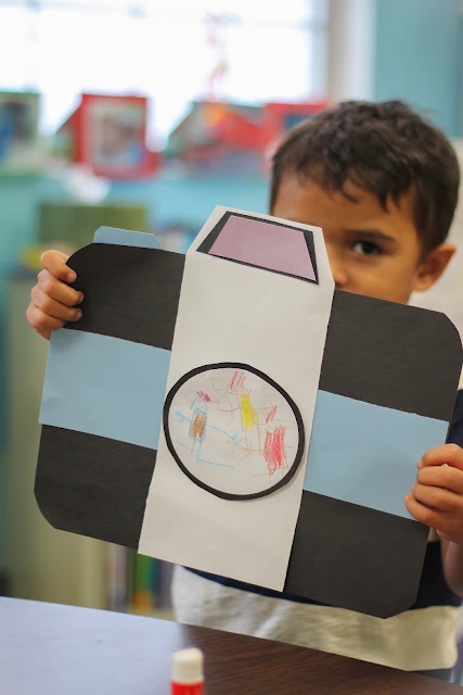 a young boy holding up a paper cut out of a rocket ship