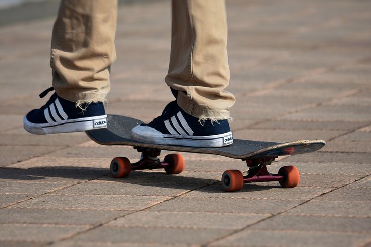 a person standing on top of a skateboard on a brick walkway with their feet up