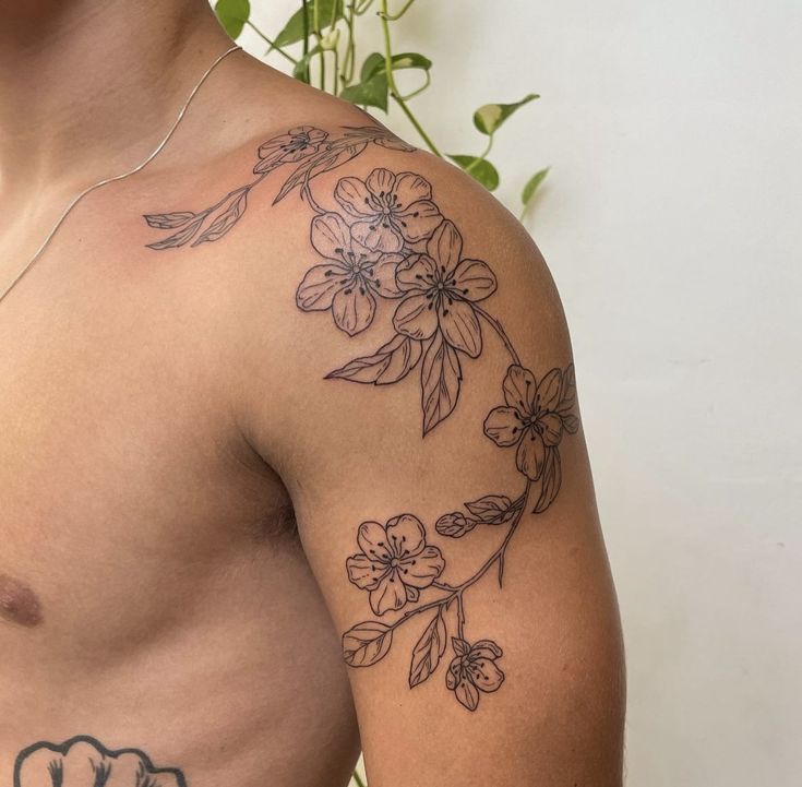 a man with a flower tattoo on his arm and chest is looking at the camera