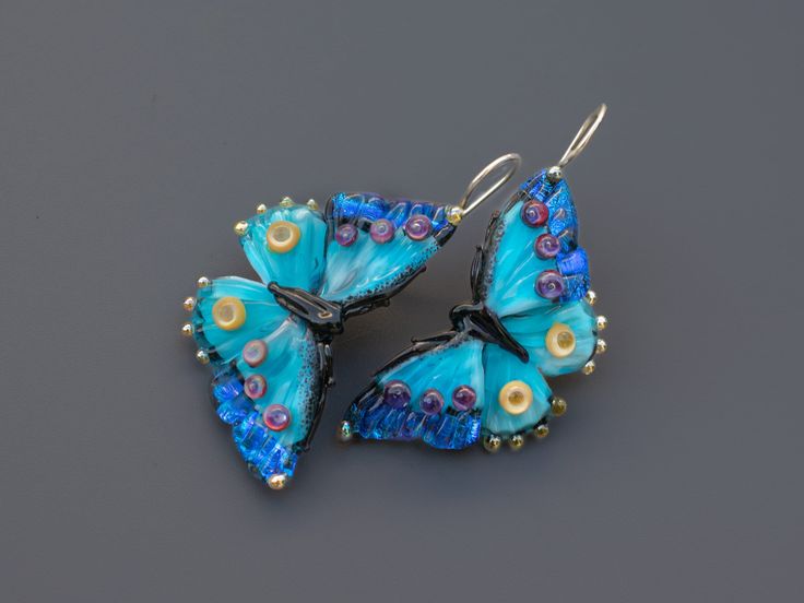 Handmade blue butterfly earrings featuring dichroic glass. Unique and lightweight, these drop earrings are crafted with care Crafted by skilled artisans, these unique earrings showcase the delicate beauty of butterflies. The iridescent blue dichroic glass wings shimmer in the light, capturing the essence of a fluttering butterfly. Lightweight and comfortable, they dangle gracefully, adding a touch of nature-inspired elegance to any outfit. Whether you're attending a garden party or simply want t Blue Butterfly Charm Dangle Earrings, Handmade Blue Butterfly Earrings, Blue Butterfly Jewelry With Butterfly Print, Blue Butterfly Charm Earrings For Gift, Blue Dangle Earrings With Butterfly Charm, Blue Butterfly Print Jewelry As A Gift, Blue Butterfly Print Jewelry For Gifts, Blue Jewelry With Butterfly Charm For Jewelry Making, Blue Jewelry With Butterfly Print For Gift