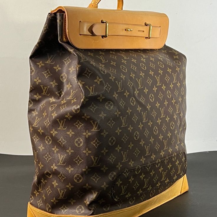 Large travel bag from the world-renowned Louis Vuitton. Crafted with meticulous attention to detail, this exquisite piece features the iconic Monogram canvas adorned with sumptuous tan cowhide leather accents, exuding sophistication and timeless elegance.  A testament to Louis Vuitton's legacy of exceptional design, this steamer bag sac showcases a near-perfect condition despite its age, reflecting the brand's commitment to quality craftsmanship. This large canvas and leather travel companion, n High-end Signature Coated Canvas Shoulder Bag For Travel, High-end Travel Shoulder Bag With Leather Trim, High-end Shoulder Bag With Leather Trim For Travel, Designer Coated Canvas Shoulder Bag For Travel, High-end Travel Backpack Shoulder Bag, Luxury Coated Canvas Backpack With Leather Handles, Luxury Backpack With Leather Handles And Coated Canvas, Luxury Monogram Canvas Travel Bag For Daily Use, High-end Travel Bag With Dust Bag