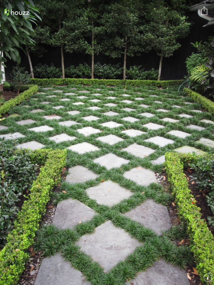 a stone walkway with grass growing on it and trees in the backgrouds