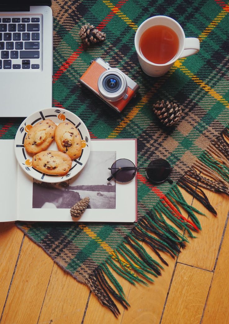 a laptop computer sitting on top of a wooden floor next to a plate of cookies