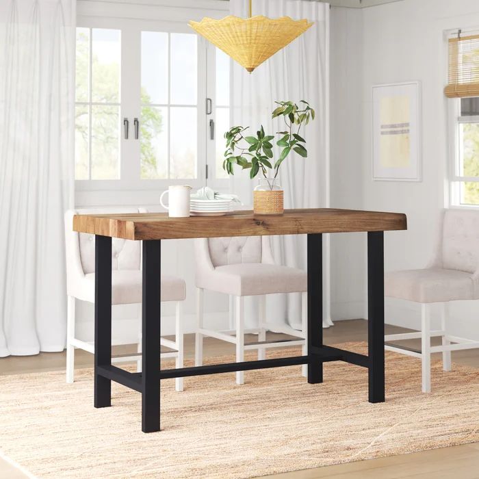 a dining room table with two chairs and a potted plant