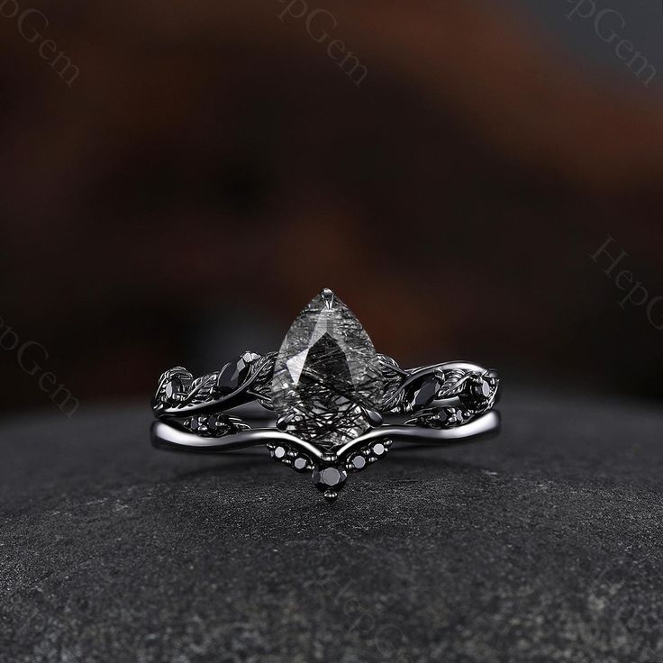 a white gold ring with an intricate design on the side and a black diamond in the middle