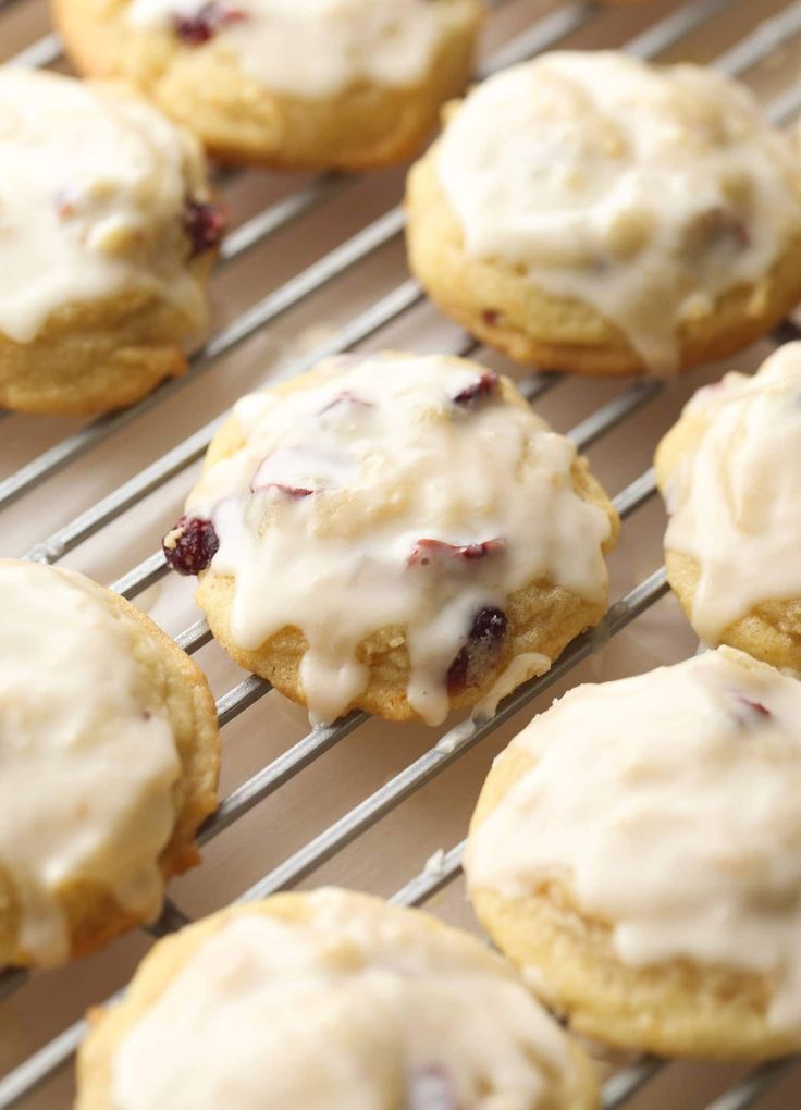 freshly baked cranberry cookies cooling on a rack with icing drizzled over them