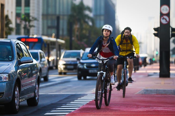 two bicyclists are riding down the street in traffic