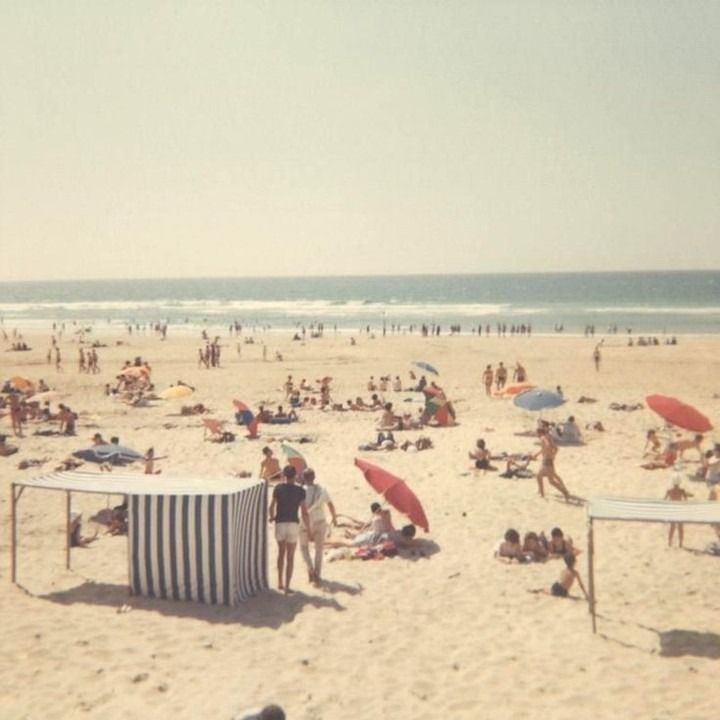 many people are on the beach with umbrellas