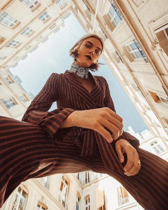 a woman is posing in front of a building with her legs spread out and wearing striped pants