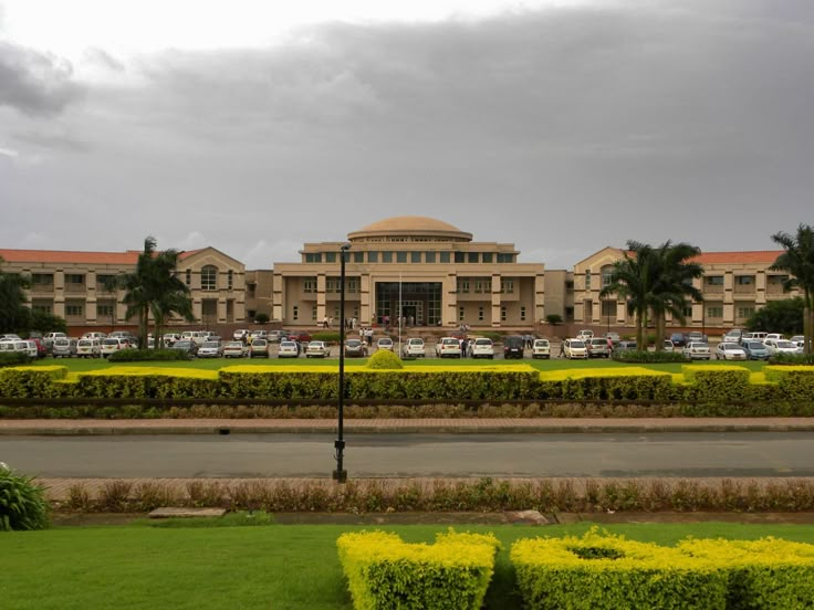 a large building sitting next to a lush green field with yellow flowers in front of it