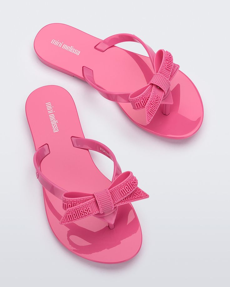 Step into summer with Mini Melissa Harmonic M Lover flip flops. The delicate bow, adorned with the iconic Melissa logo adds a romantic touch to this timeless silhouette. These are ultra-lightweight and practical, making them the perfect choice for every warm-weather outfit. Plus, you can match your mini! Casual Summer Flip Flops With Bow, Summer Bow Flip Flops With Open Toe, Summer Beach Flip Flops With Bow, Chic Pink Flip Flops For Summer, Pink Feminine Sandals With Bow, Adjustable Bow Sandals For Beach, Summer Bow Sandals For Beach, Feminine Pink Sandals With Bow, Trendy Beach Sandals With Bow