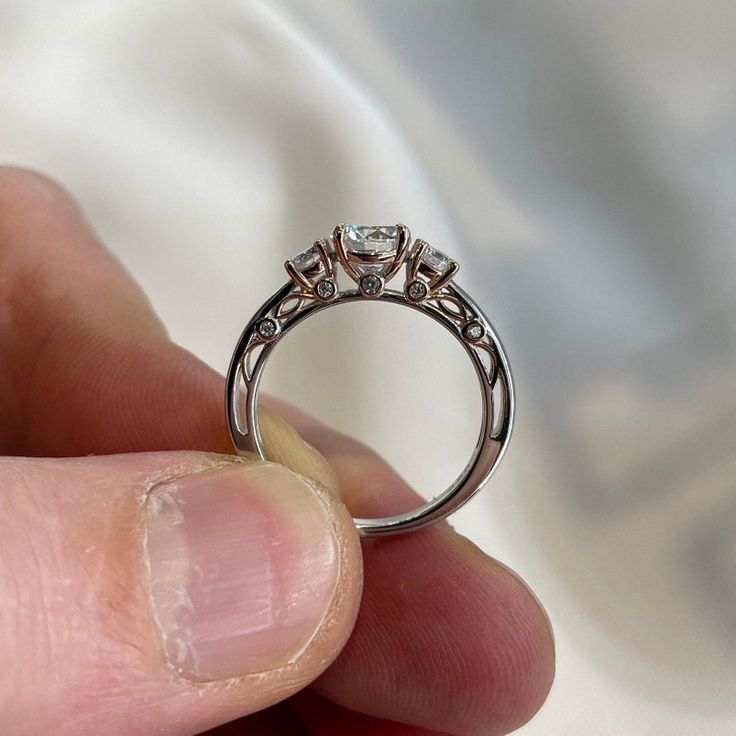 a hand holding a ring with three diamonds on it