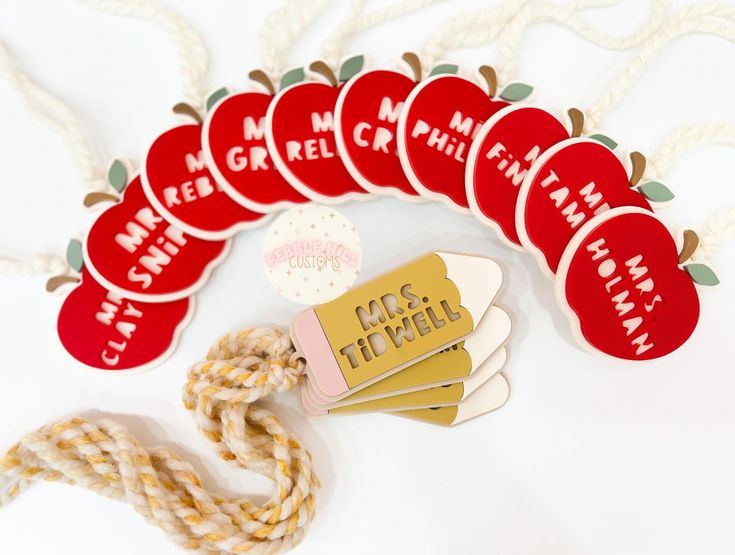 red and white tags with words on them sitting next to rope, apple shaped magnets