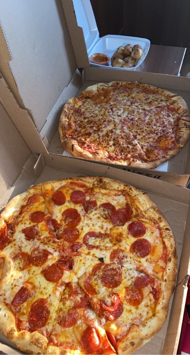 two pizzas sitting in boxes on top of a table