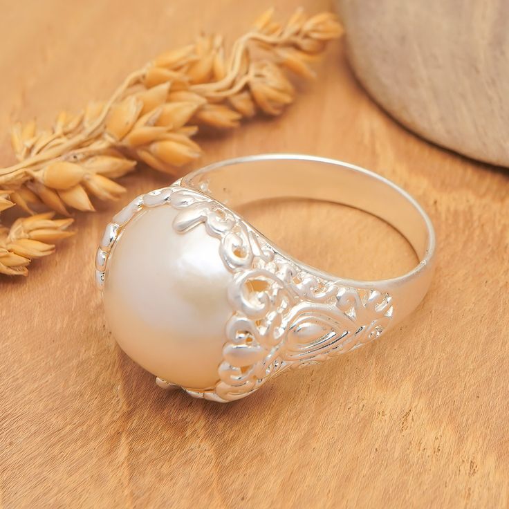 Ancient cultures often associated pearls with feminine energies, considering them sacred gifts from the ocean. Today, this jewel is a synonym for beauty, innocence and grace, which is why Balinese artisan Diah Arini chooses a cultured pearl to be the protagonist of her newest creation. This sterling silver domed cocktail ring has a matte finish that adds a charming illusion to the traditional motifs around the band, creating the perfect accessory for formal or casual occasions. Handmade Round Pearl Ring, Handmade Pearl Ring As A Gift, Gift Pearl Cabochon Ring, Wedding Pearl Rings With Pearl Pendant, Silver Pearl Ring With Charm For Wedding, Vintage Pearl Ring As Gift, Silver Ring With Pearl Charm For Wedding, Vintage Pearl Rings As Gift, Pearl White Rings With Pearl Drop For Gift