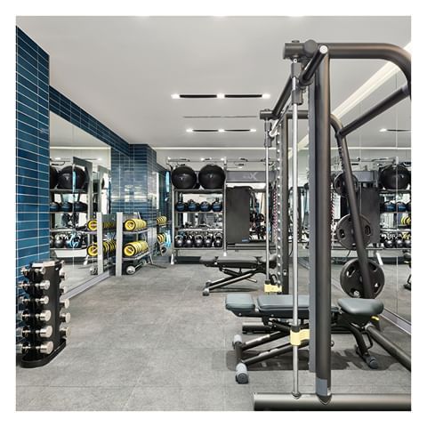 an empty gym with rows of exercise equipment and blue tiled walls in the back ground