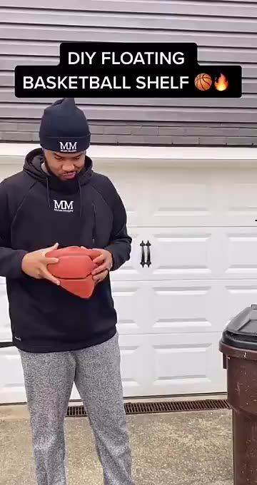 a man standing in front of a garage holding a red object with the words diy floating basketball shelf on it