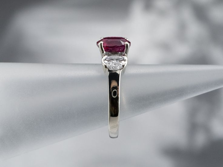 Always in style, rings such as this one can be worn as engagement rings, birthstone rings, or just for special occasions. We've set the center of this one with a high-quality, glowing red ruby. The side stones are bright white diamonds, reflecting plenty of light into the center stone. As an engagement ring will look well with a variety of bands, from a plain golden circle to a ruby and diamond eternity band. Metal: 14K White Gold Gem: Ruby 2.02 Carats Gem Measurements: 8.0 x 6.0 mm, Oval Accents: 8 Diamonds totaling .50 Carats, G in Color, SI1 in Clarity Ring Size: 6.75 Marks: “14K MFP” Stamped on the inside band Luxury Three Stone Ruby Ring, Oval Red Ruby Ring With Three Stones, Classic Three Stone Ruby Ring, Classic Three-stone Ruby Ring, Classic Three Stone Ruby Ring With Diamonds, Formal White Gold Ruby Ring With Three Stones, Classic Red Three Stone Diamond Ring, Platinum Rings With Red Diamond Accents, Red Platinum Rings With Diamond Accents