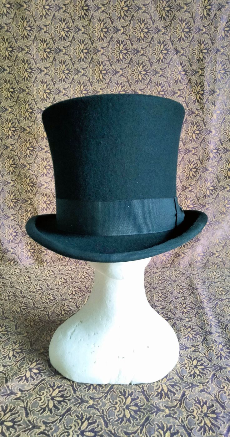 "Victorian style top hat in merinos wool, dome h 15 cm, brim 5 cm, outer band in black cotton h 4 cm, interior lined in white satin, internal sweatband in soft black leather. Entirely hand-made and sewn, the wing has the typical \"curl\" with the grosgrain finish sewn and turned used for the top hats and bowler hats of the 19th century." Classic Fitted Winter Costume Hats And Headpieces, Winter Formal Black Costume Hats And Headpieces, Formal Black Costume Hats For Winter, Black Formal Winter Costume Hat, Formal Black Winter Costume Hat, Black Mini Hats For Formal Winter Occasions, Winter Top Hat With Short Brim, Fitted Black Top Hat With High Crown, Formal Black Winter Top Hat