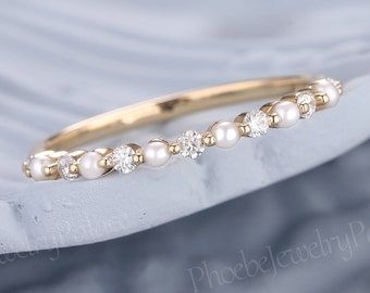 a gold ring with pearls on it sitting on top of a white piece of cloth