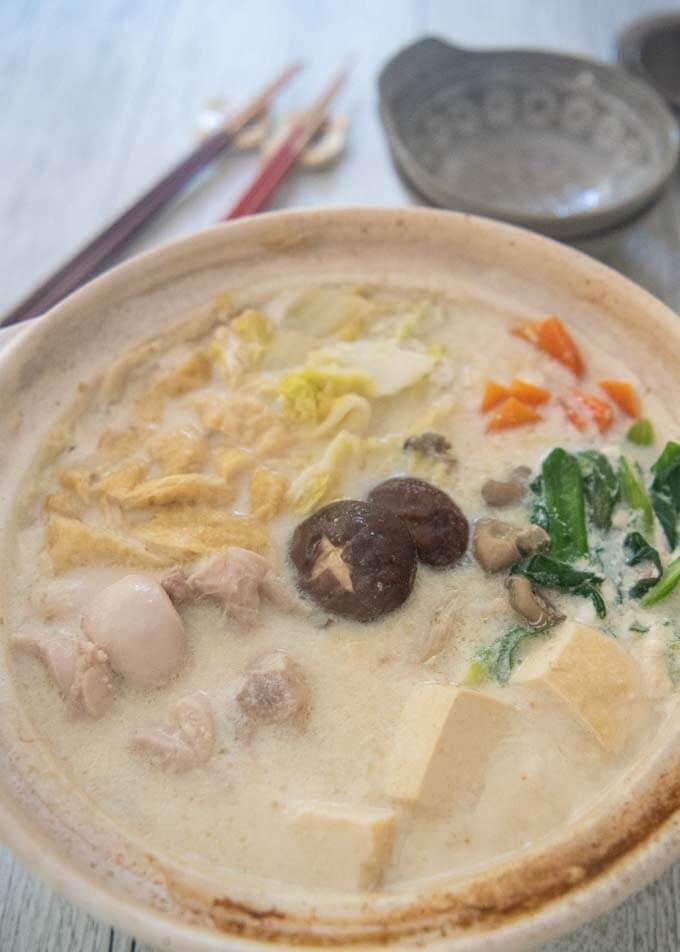 a white bowl filled with soup next to chopsticks on top of a table