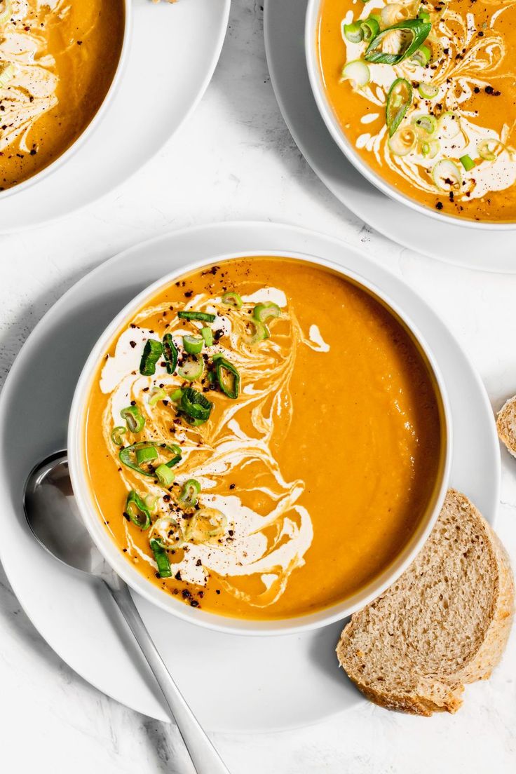 three bowls of soup with bread on the side