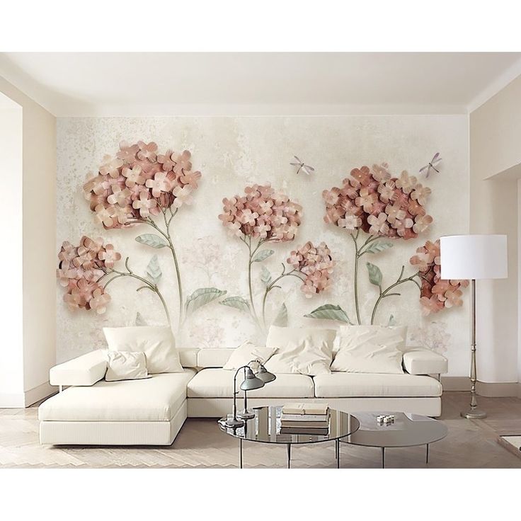 a living room with white furniture and pink flowers on the wall