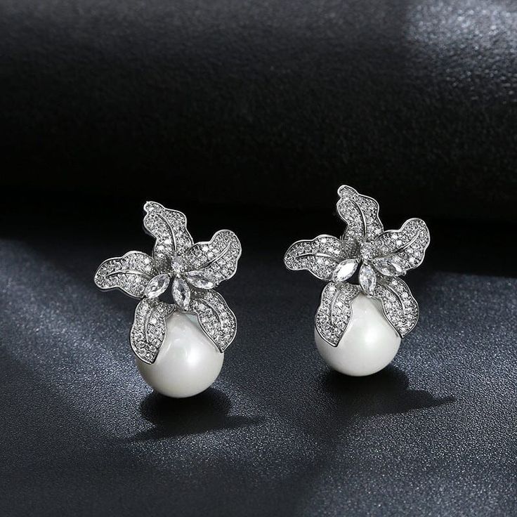 Be the center of attention with these beautiful LILY PEARL EARRINGS. Featuring a delicate LILY design, these earrings are sure to be a perfect addition to any occasion. Pearls delicately embellish the petals- creating a sophisticated and timeless look. Floral Dress Shoes, Lily Earrings, Lily Design, Center Of Attention, Silver Pearl Earrings, Crystal Hoop Earrings, Beaded Clutch, Silver Pearls, Real Gold