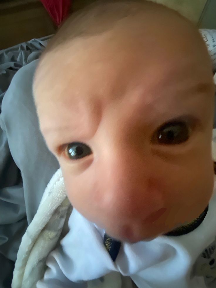 a bald baby wearing a white shirt and tie with his head tilted to the side