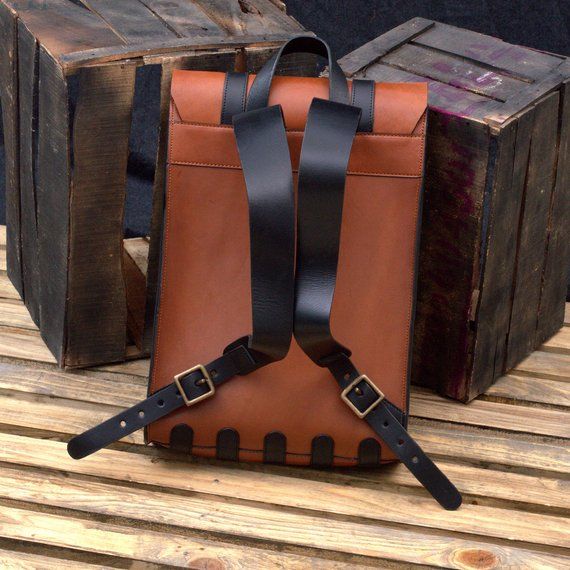 a brown and black backpack sitting on top of a wooden table next to two boxes