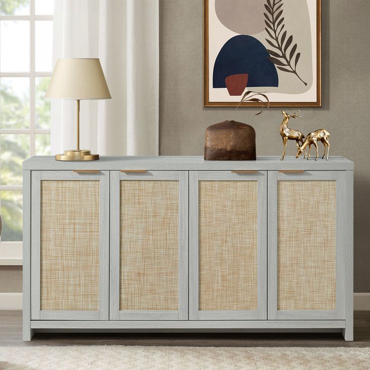 a sideboard with three doors and two lamps on it in a living room next to a window