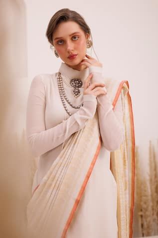 Ivory jamdani saree with tassels on the pallu. Paired with a turtle neck silk chiffon kurta blouse.
Components: 2
Pattern: Woven
Neckline: Turtle
Sleeve Type: Long
Fabric: Saree: Jamdani, Blouse: Silk Chiffon
Color: Ivory
Other Details: 
Length:
Saree: 5.5 mtrs
Blouse: 30 inches
Note: Jewellery worn by the model is not for sale.
Occasion: Puja - Aza Fashions Elegant Handloom Wedding Dresses, Traditional Long Sleeve Blouse With Sheer Dupatta, Traditional Designer Wear Off White Blouse Piece, Elegant Long Sleeve Handloom Traditional Wear, White Zari Work Blouse For Eid, White Anarkali Designer Blouse Piece, White Anarkali Blouse With Sheer Dupatta, Designer Anarkali White Blouse Piece, Designer White Blouse With Sheer Dupatta