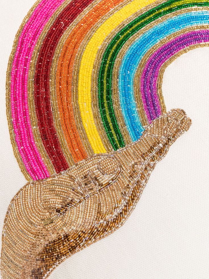 a close up of a piece of art made out of beads with a rainbow in the background