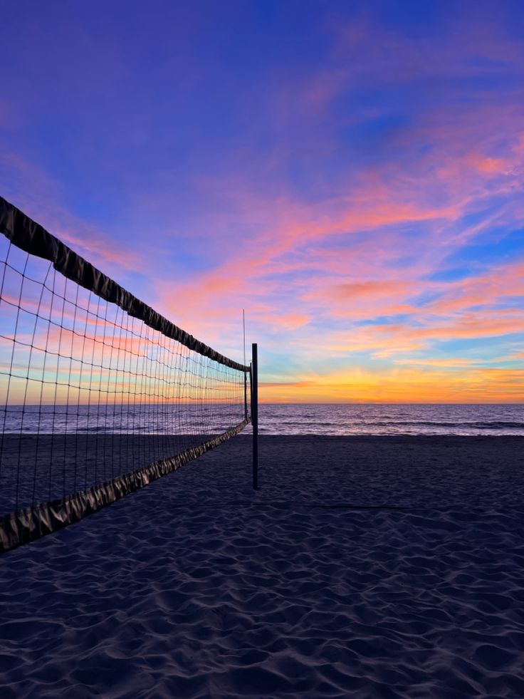 a volleyball net on the beach at sunset