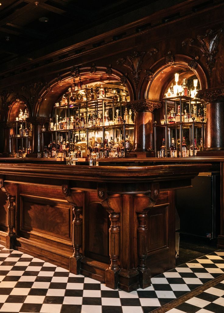 an old fashioned bar with lots of bottles on the shelves and black and white checkered floor