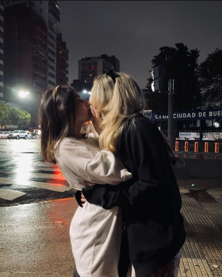 two women are kissing in the street at night