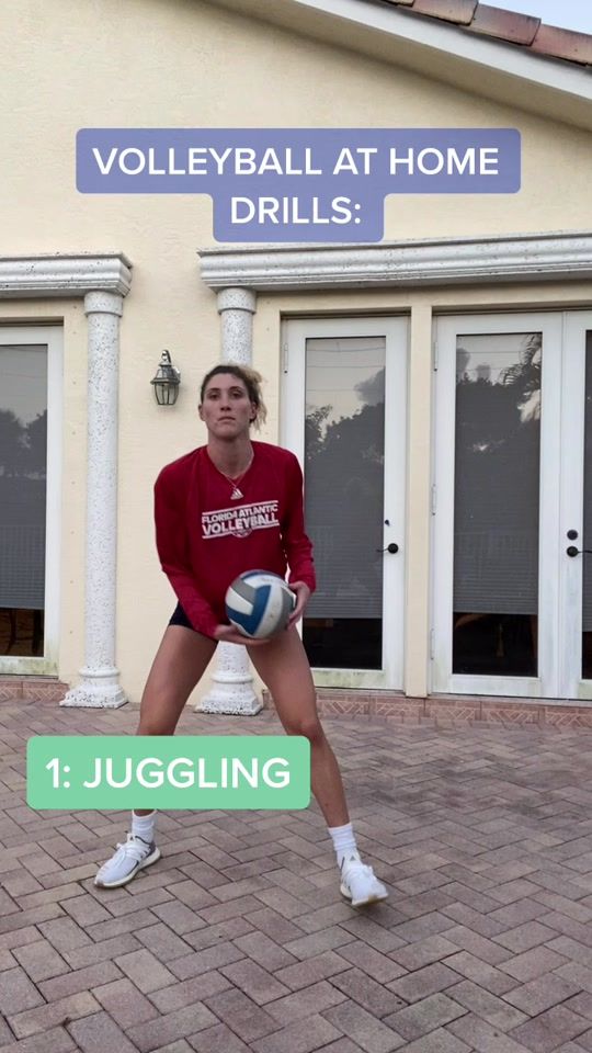 a woman holding a volleyball ball in front of a building