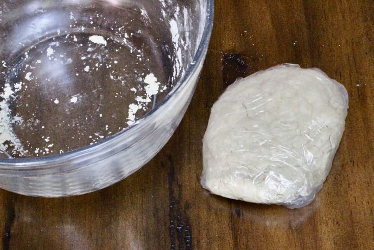 a glass bowl filled with white powder next to a rock on top of a wooden table