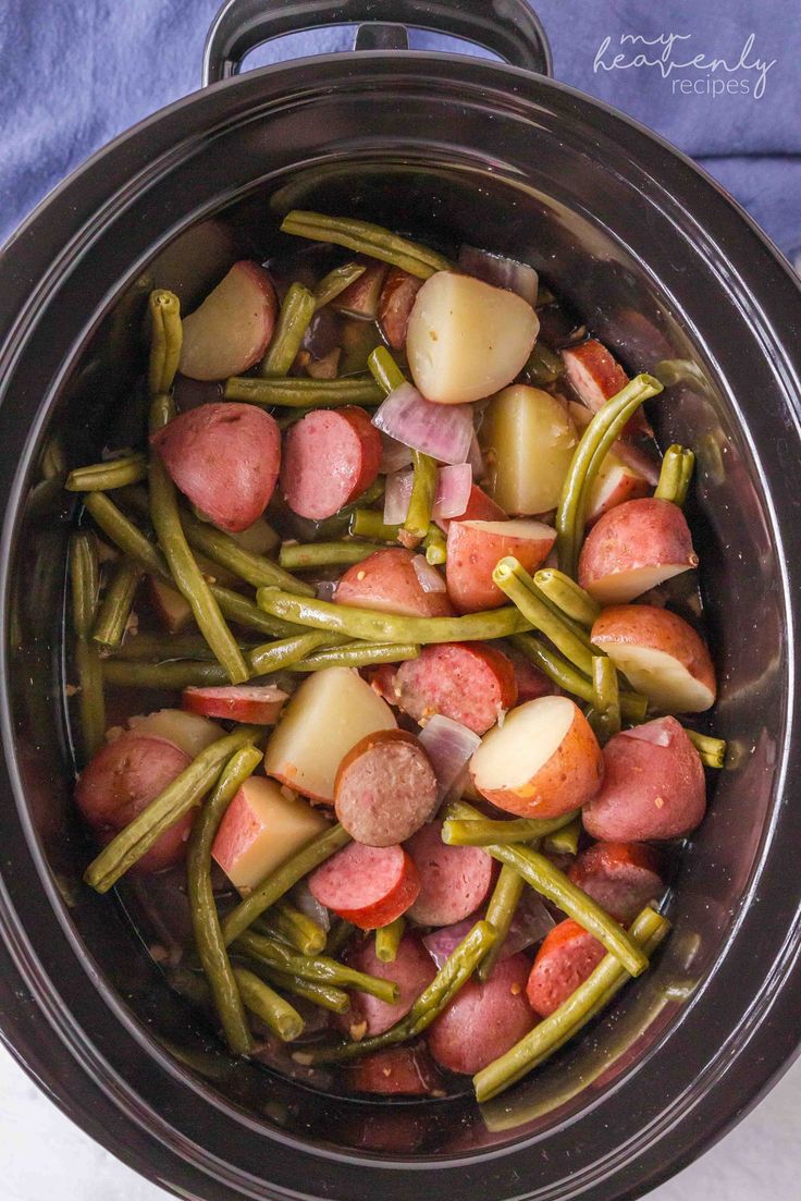 a crock pot filled with green beans, potatoes and ham cooked in the slow cooker