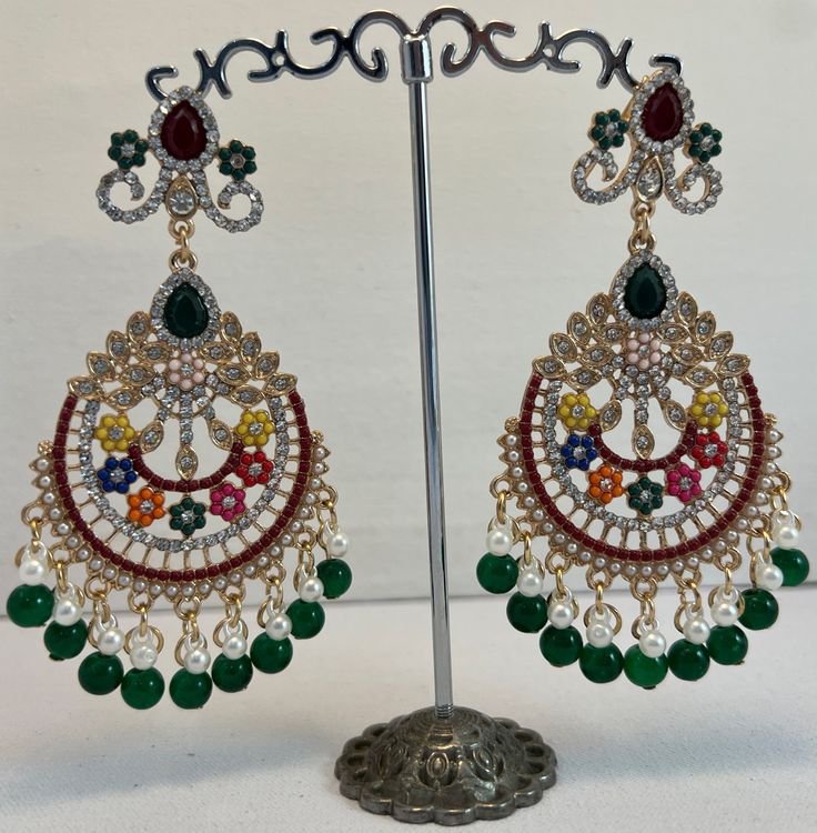 Dazzle in the rich tapestry of culture with these exquisite Multicolor Traditional Chandelier Earrings. A stunning array of vibrant gemstones and delicate pearls are meticulously arranged in an ethnic motif, creating an eye-catching display of elegance and craftsmanship. Each earring features a luxurious cascade of black and white pearls, adding a classic touch to the ornate design. Perfect for adding a splash of color to evening wear or elevating traditional attire, these earrings are a celebra Multicolor Chandbali Earrings With Intricate Design, Multicolor Chandbalis With Intricate Design For Festivals, Multicolor Chandbali Jhumkas With Intricate Design, Fusion Style Multicolor Earrings For Festivals, Festive Traditional Chandelier Earrings, Elegant Multicolor Chandbalis For Celebrations, Multicolor Chandbalis With Intricate Design For Celebration, Elegant Multicolor Chandbalis With Latkans, Elegant Multicolor Meenakari Chandbalis