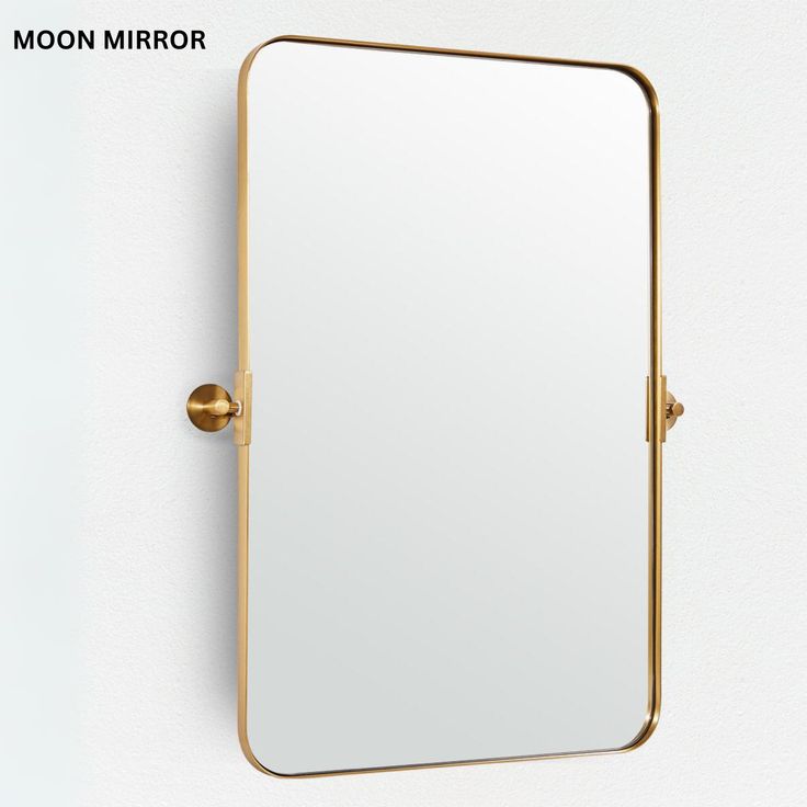 a mirror mounted to the side of a wall next to a gold hook on a white wall