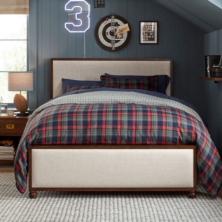 a bedroom with blue walls, plaid bedding and a clock above the headboard