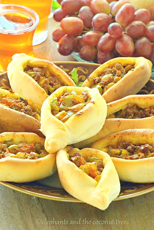 hot dogs stuffed with chili and cheese on a plate next to grapes, honey - syrup, and beer