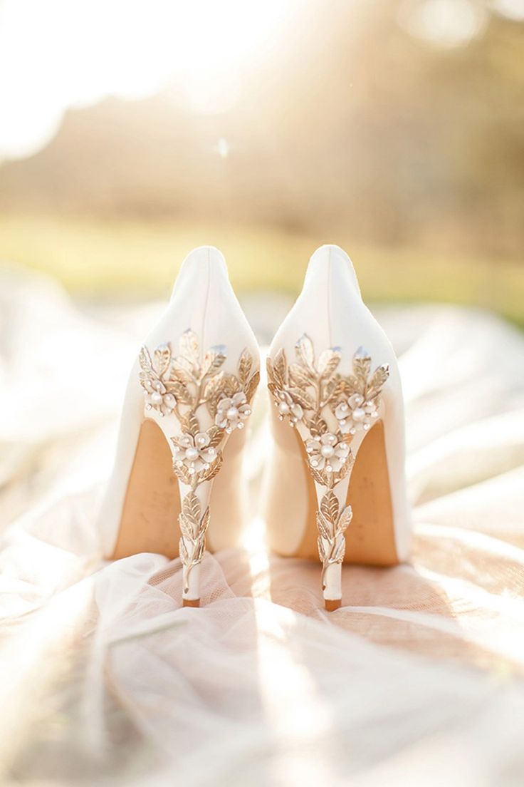 a pair of white high heeled shoes sitting on top of a bed