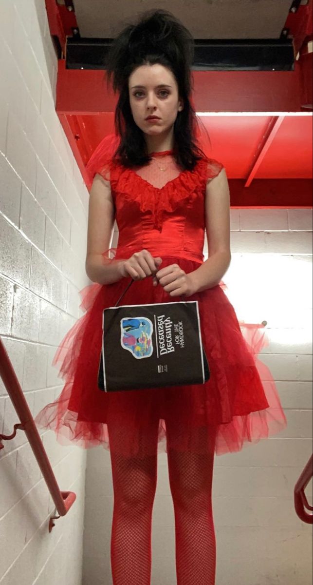 a woman in a red dress holding a black bag